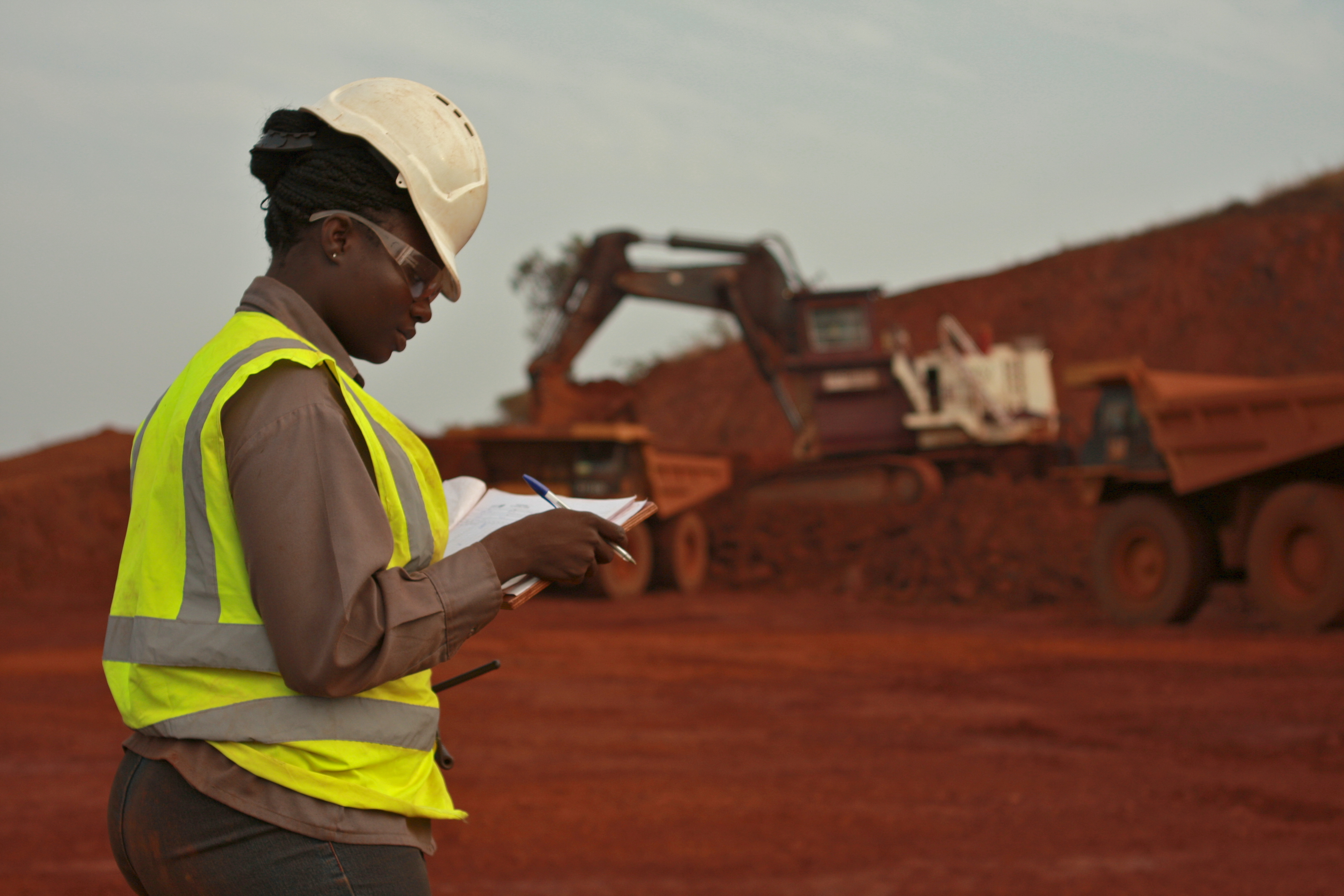 Mine supervisor in high-visibility gear recording notes at an iron-ore operation