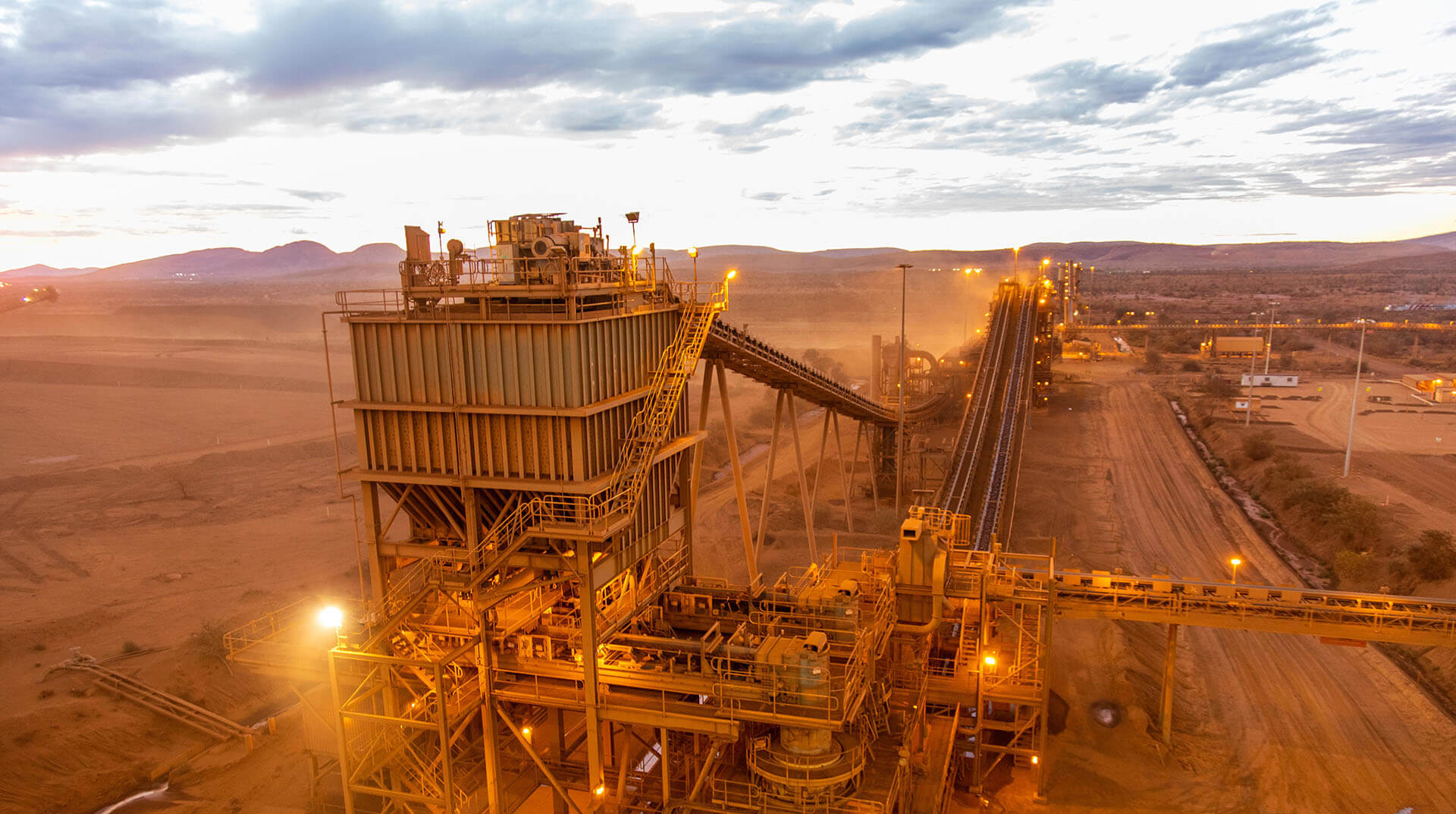 Ore processing plant and conveyors in dust at sunset, West Angela's, Rio Tinto iron ore operations, Western Australia
