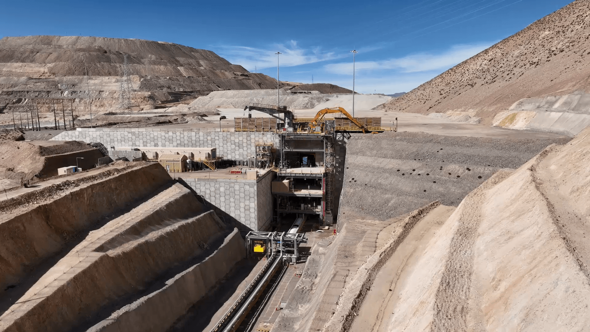 Aerial view of a large open-pit mine with haul trucks working the terraced benches in South American Copper Mine.
